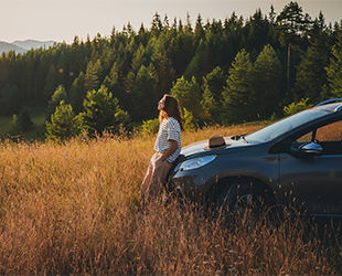 Young beautiful woman traveler enjoying the sunset in the mountains while traveling by car