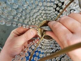 Remontage de perles en cristal sur un lustre.