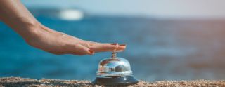 Close up of female hand ringing service bell against the ocean b